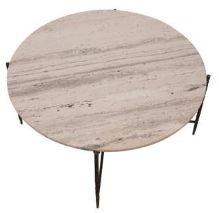 A round beige marble cocktail table with grey veining, supported by hammered metal legs.