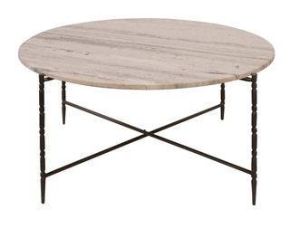 A round beige marble cocktail table with grey veining, supported by hammered metal legs.