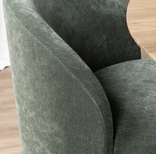 Close-up of a green upholstered chair with a wooden table in the background