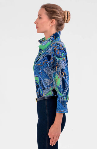 A woman wearing a colorful geometric patterned shirt with shiny brass buttons, styled with the sleeves rolled up to the elbows.