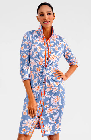 A model wearing a Gretchen Scott Twist & Shout Dress with ¾ sleeves, a center front racer stripe banding, and a floral pattern in periwinkle colors.