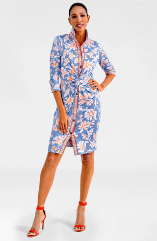 A model wearing a Gretchen Scott Twist & Shout Dress with ¾ sleeves, a center front racer stripe banding, and a floral pattern in periwinkle colors.