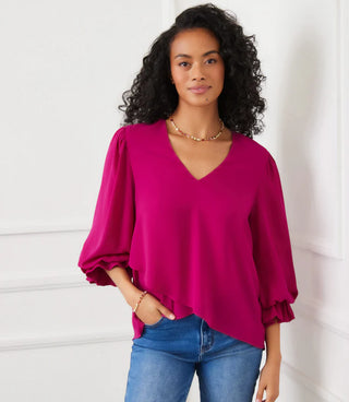 Woman wearing a bright pink blouse with balloon sleeves against a white background. Karen Kane V Neck Layered Sleeve Asymmetric Top, Magenta
