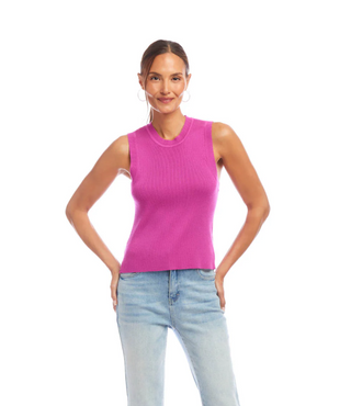 A woman wearing an orchid pink ribbed sweater tank top with a crew neck, sleeveless design, paired with light blue jeans.