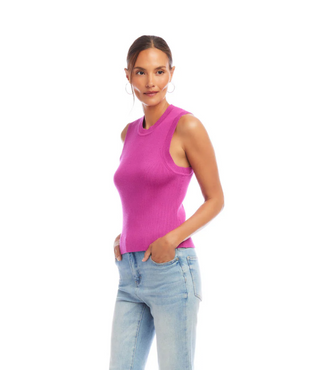 A woman wearing an orchid pink ribbed sweater tank top with a crew neck, sleeveless design, paired with light blue jeans.