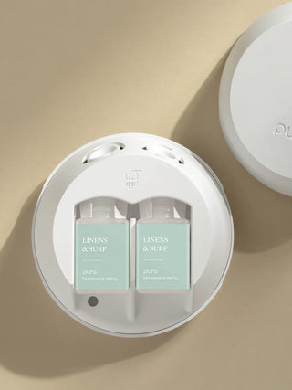 A Pura fragrance vial refill with its packaging, in a light mint green color with floral graphics, the product is labeled 'Linens & Surf'.