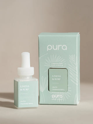 A Pura fragrance vial refill with its packaging, in a light mint green color with floral graphics, the product is labeled 'Linens & Surf'.