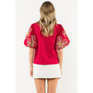Woman wearing a THML burgundy blouse with floral sleeves on a white background back