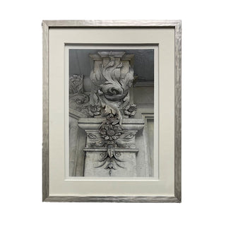 A framed artwork featuring an intricate architectural design, predominantly in gray and beige tones.