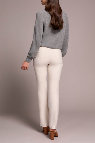 Person wearing a gray sweater and white pants against a neutral background