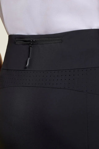 A woman wearing a white sleeveless top and black skort with pockets.