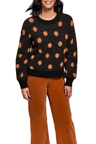 Person wearing a black sweater with orange polka dots and brown pants against a neutral background. Tribal Long Sleeve Crew Neck Sweater in Black