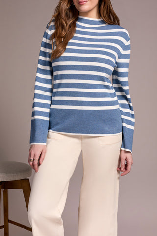 Person wearing a blue and white striped sweater with beige pants on a plain background