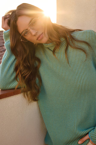 Woman wearing a blue and green sweater with a blurred background