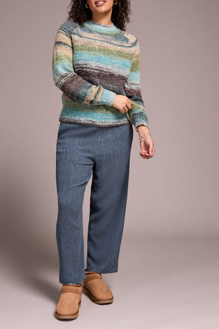 Person wearing a striped sweater and blue jeans against a plain background
