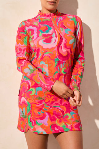 A model wearing a long sleeve performance top with a vibrant bloom design in pink, orange, and green colors.