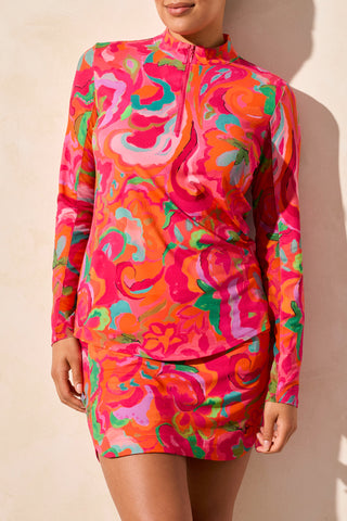 A model wearing a long sleeve performance top with a vibrant bloom design in pink, orange, and green colors.