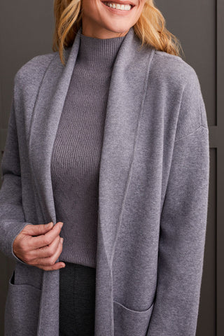 A person wearing a heathered charcoal open-front coatigan with patch pockets over a gray sweater and black pants.
