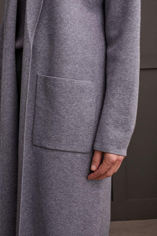 A person wearing a heathered charcoal open-front coatigan with patch pockets over a gray sweater and black pants.