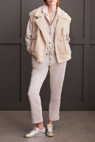 A model wearing a sherpa and suede vest in a latte color with silver accent buttons.