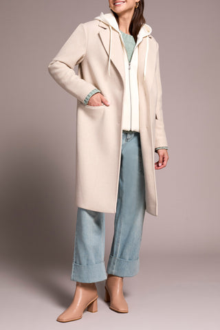 Woman wearing a long beige coat with a plain background