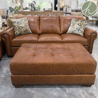 Brown leather sectional sofa with ottoman in a showroom setting