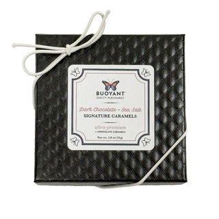 Black quilted gift box with a label for Buoyant Dark Chocolate + Sea Salt Signature Caramels on a white background.