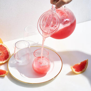 A clear acrylic beverage pitcher with a lid, filled with a refreshing beverage.