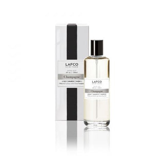 A clear bottle of LAFCO Champagne Room Mist with a black cap, displayed in front of its black and white packaging box.