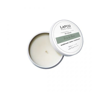 A LAFCO Feu de Bois travel candle in a white tin container with the lid off, showing the white candle inside.