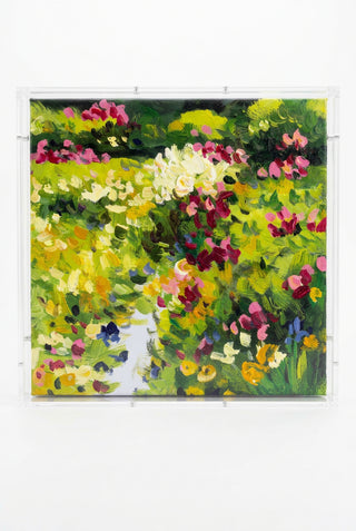 An impressionistic floral painting in a clear acrylic frame, featuring vibrant green foliage and multicolored flowers including pink, yellow, white, and purple.
