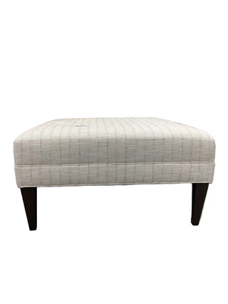 Patterned ottoman with wooden legs on a white background