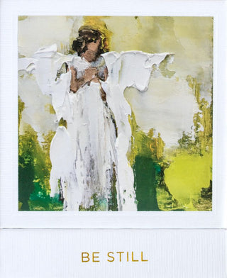 A candle with a white wick, placed in a clear glass holder, with a card behind it featuring an artwork of an angel in a field of green and yellow. Anne Neilson Be Still Candle