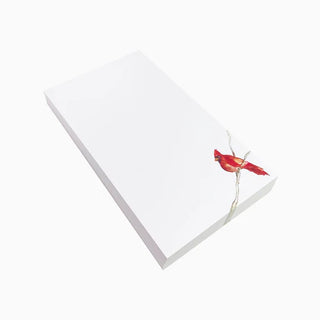 A white notepad with a picture of a red cardinal sitting on branch, placed on a plain background, anne neilson 
