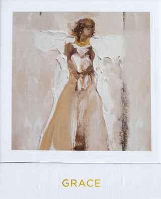 A hand-poured white candle in an artisan glass, with a card beside it featuring a painting of a angel. The candle is labeled 'GRACE', Anne Neilson Grace Candle
