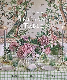 Cover of the book 'At the Artisan's Table' featuring a beautifully set dining table with floral patterns and ornate tableware. At the Artisan's Table Book.