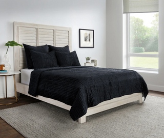 Bedroom with a bed featuring black bedding and a white headboard.