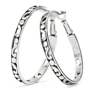 A pair of silver hoop earrings with intricate scrollwork design. Brighton