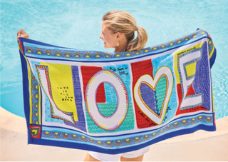 Woman holding a colorful towel with 'LOVE' printed on it by a pool.  Brighton 