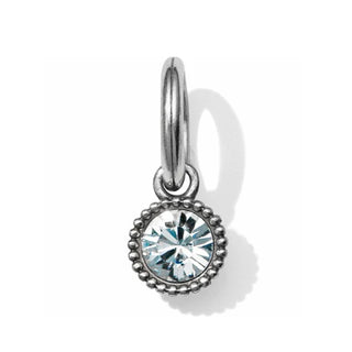 A faceted crystal amulet with a metallic ring on top, set against a textured background. Brighton
