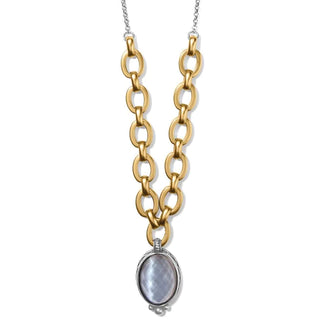 A gold-colored chain necklace with a round glass pendant set in a gold frame, on a cool chain link. Brighton