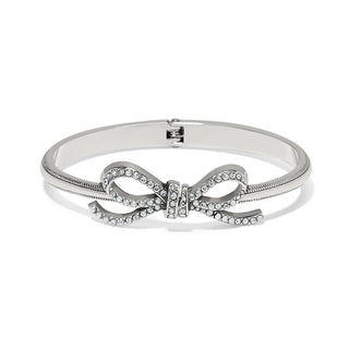 A silver-colored Brighton Illumina Bow bangle bracelet with a hinged closure and crystal embellishments in the shape of a bow.