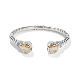 A silver-golden colored bracelet with a solid pattern and a crystal embellishment in the center, featuring a hinged closure. Brighton