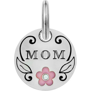 A silver charm with the text 'MOM' and 'LOVE' engraved on it, accompanied by a floral design and a pink flower with a gemstone center. Brighton