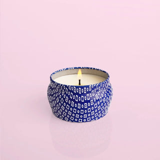 Capri Blue Volcano tin candle in a blue patterned mini tin on a pink background.