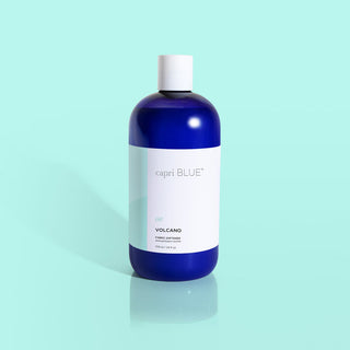 A blue bottle of Capri Blue Volcano fabric softener against a light blue background.