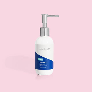 A bottle of Capri Blue Volcano hand lotion with a pump dispenser, predominantly white in color with blue accents.