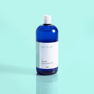 A blue bottle of Capri Blue Volcano laundry detergent against a light blue background.
