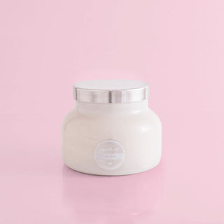 A white, 19 oz Capri Blue candle jar with a silver lid, labeled 'Volcano', against a pink background.