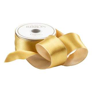A spool of Caspari satin ribbon in gold and ivory colors, partially unrolled to show the reversible quality.